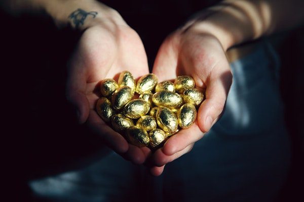 Person with tattoos holden gold foil nest egg investments in their hands as assets to retire on..