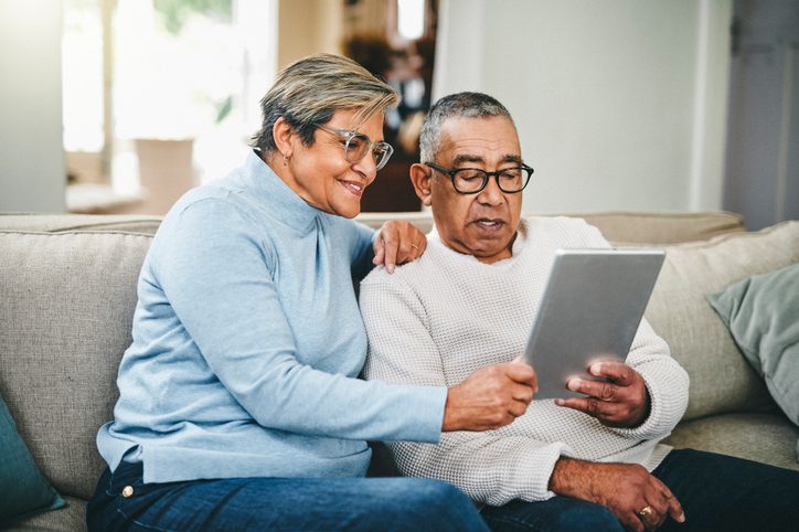 Senior couple reading reviews of funeral insurance policies online.